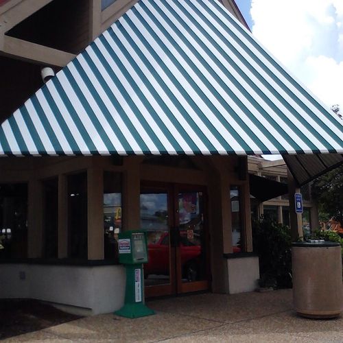 A large walkway cover shades the entrance to an unlabeled wooden business entrance