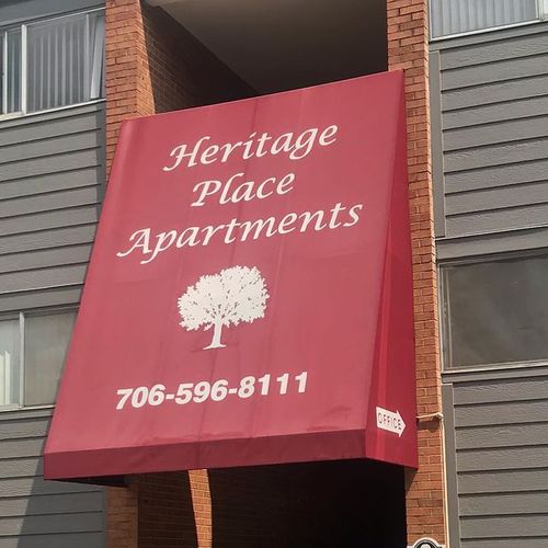 An awning that reads 'Heritage Place Apartments - 706-596-8111' covering a walkway