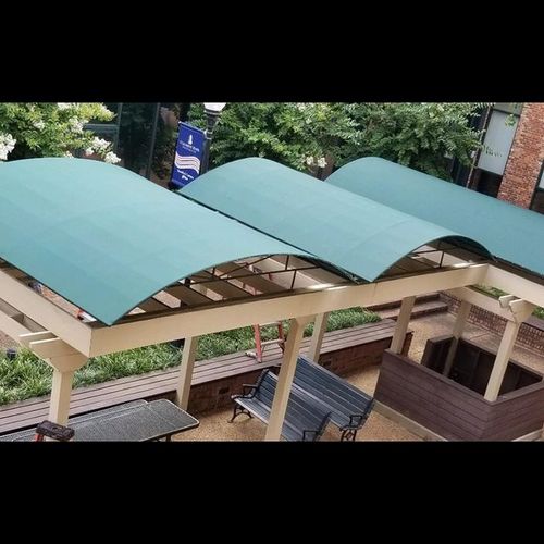 Three wooden shade covers over a public seating area