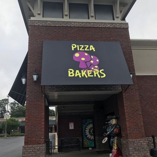 An awning that reads 'Pizza Bakers' with an image of several mushrooms covers the entrance to the Mellow Mushroom building