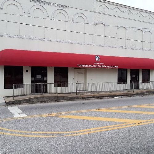 A long bullnose awning that reads 'Tuskegee-Macon County Head Start' covers the walkway in front of a large building