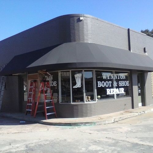 A storefront awning wraps around a curved building whose windows read 'Wynnton boot and shoe repair'