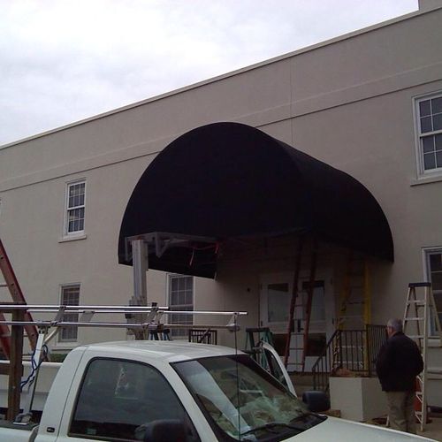 A large walkway awning shades the entrance to a large brick building