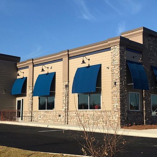 Several windows and an entrances to a Culver's building are covered by convex awnings