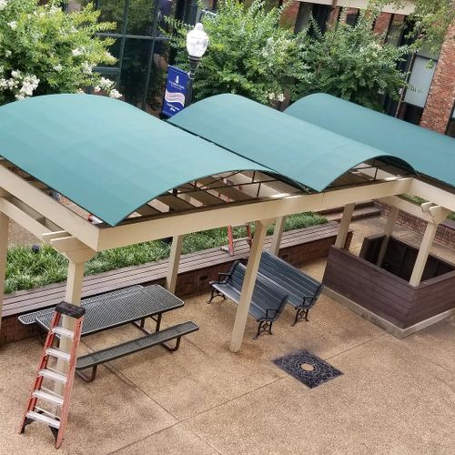 Three wooden pergolas shade a public seating area at the CSU Yancey Center