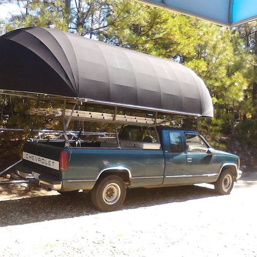 A large bullnose awning is en route to its destination, carried via a Chevrolet pickup truck