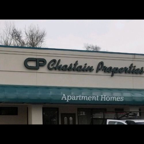A long waterfall awning on the front of a building labeled 'Chastain Properties' reads 'Apartment Homes'