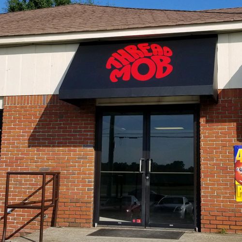 A canvas awning over the door to a brick building reads 'Thread Mob'