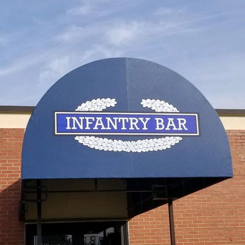 A long half-round awning shades the walkway into Infantry Bar