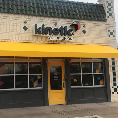 A storefront awning shades the doorway to the Kinetic Credit Union building