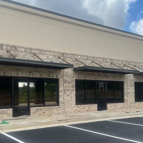 Several metal awnings shade the entrance to a commercial building