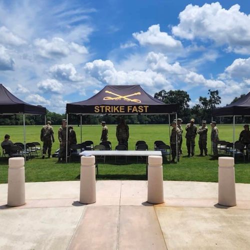 Several canopies shade seating at a Fort Benning event