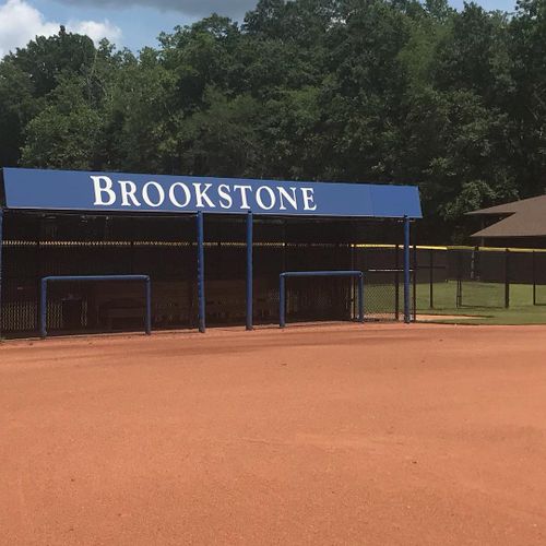 A large awning shades the dugout at a baseball field for Brookstone School