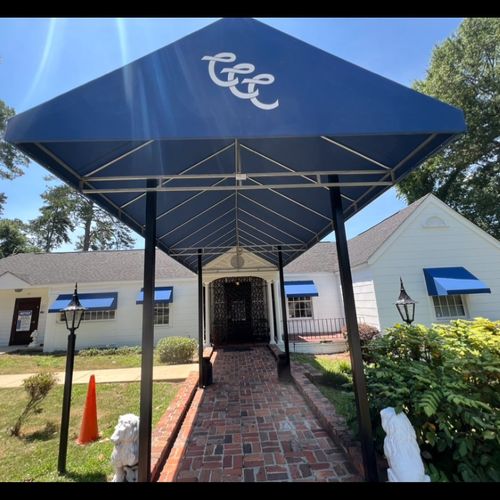 A canvas awning with metal supports shades the walkway and entrance of Country Club of Columbus