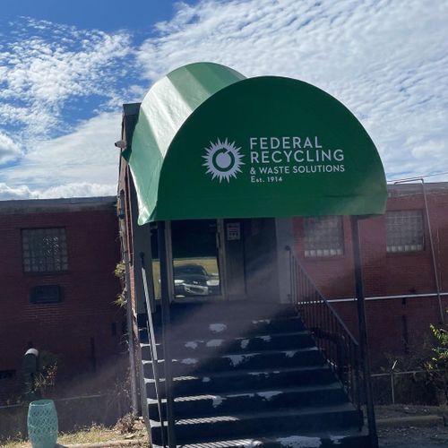 A canvas awning that reads 'Federal Recycling & Waste Solutions - Est. 1914' shades the stairway and entrance of an industrial building