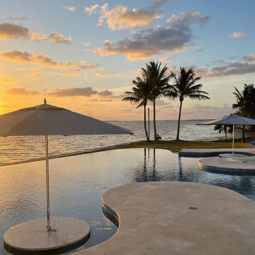 two small islands feature stationary umbrellas at a beachside resort at sunset