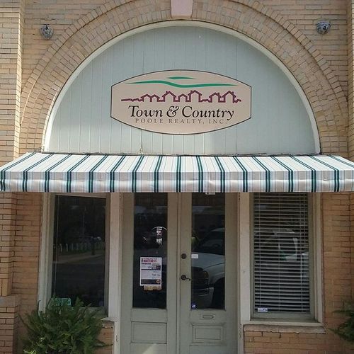An awning shades the entrance to a building whose sign reads 'Town & Country - Poole Realty, Inc.'
