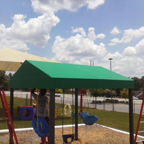 A small canopy covers swingset on a playground