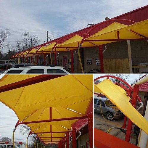 A series of pyramid-shaped awnings covering several stalls of a car wash