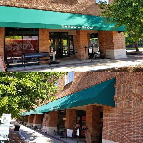 Two long storefront awnings read 'The Market on Broadway' shade the entrances to a large brick building